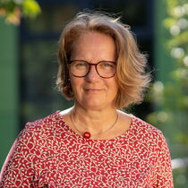 Portraitfoto Stefanie Ganz - Sie trägt mittelblondes, kinnlanges Haar, eine Brille und ein rot-weiß gemustertes Kleid.