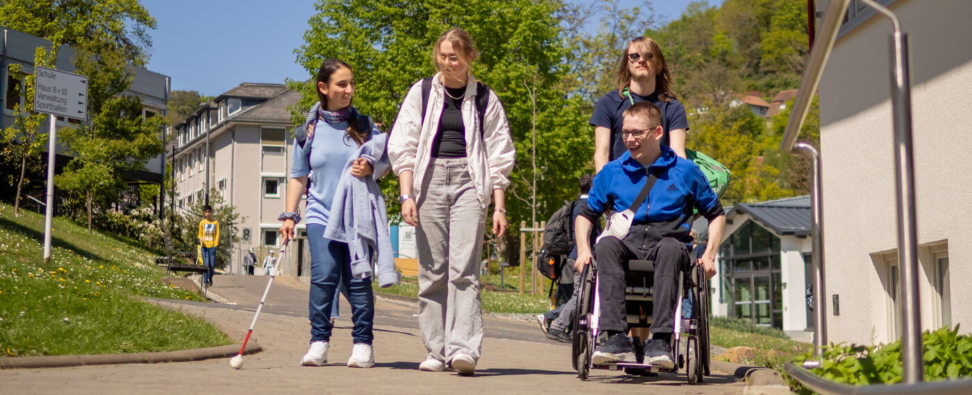 Eine Gruppe von vier Schüler*innen auf dem Campus