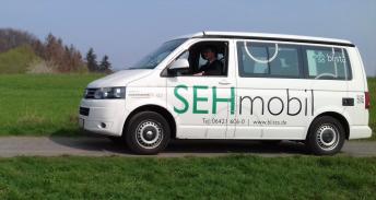 Der weiße Kleinbus trägt die Aufschrift SEHmobil in großen Lettern