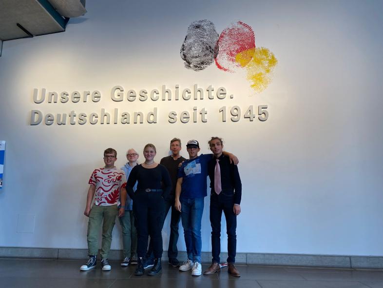 Die fünf Jugendlichen stehen mit Günther Wagner vor einer Wand, an der drei riesige Fingerabdrücke in schwarz, rot und gold und darunter der Schriftzug: "Unsere Geschichte, Deutschland seit 1945" angebracht sind.
