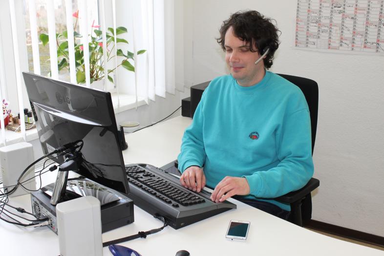 Ein Mann arbeitet am blindenspezifisch ausgestatteten PC-Arbeitsplatz