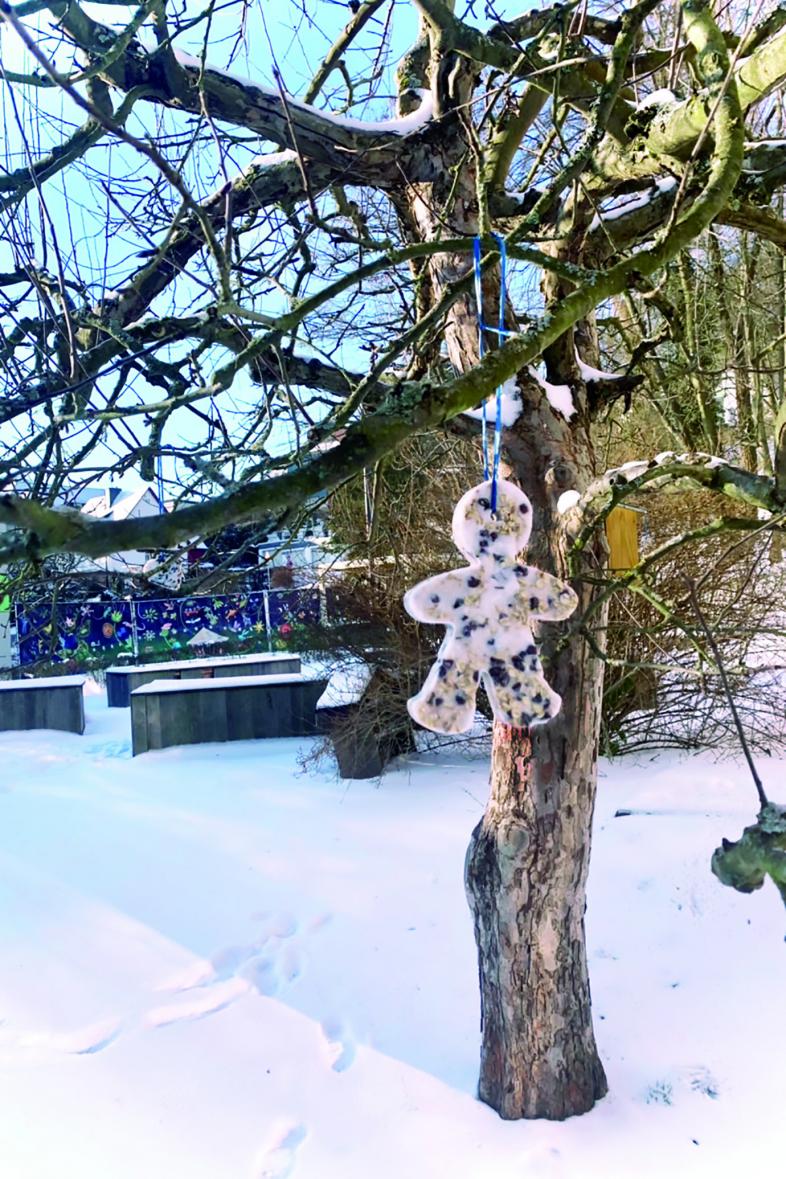 Ein selbstgemachtes Vogelfuttermännchen hängt im Baum