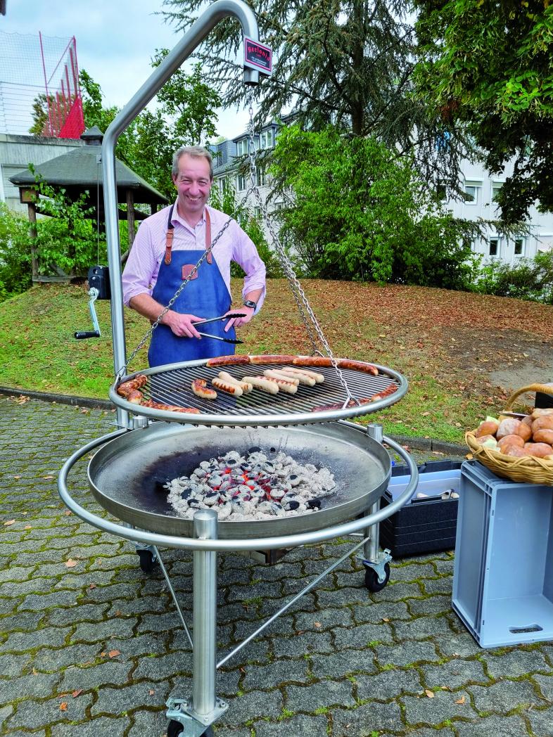 Patrick Temmesfeld, stellvertretender Vorsitzender der blista steht als Grillmeister am Schwenkgrill und grillt Würstchen.