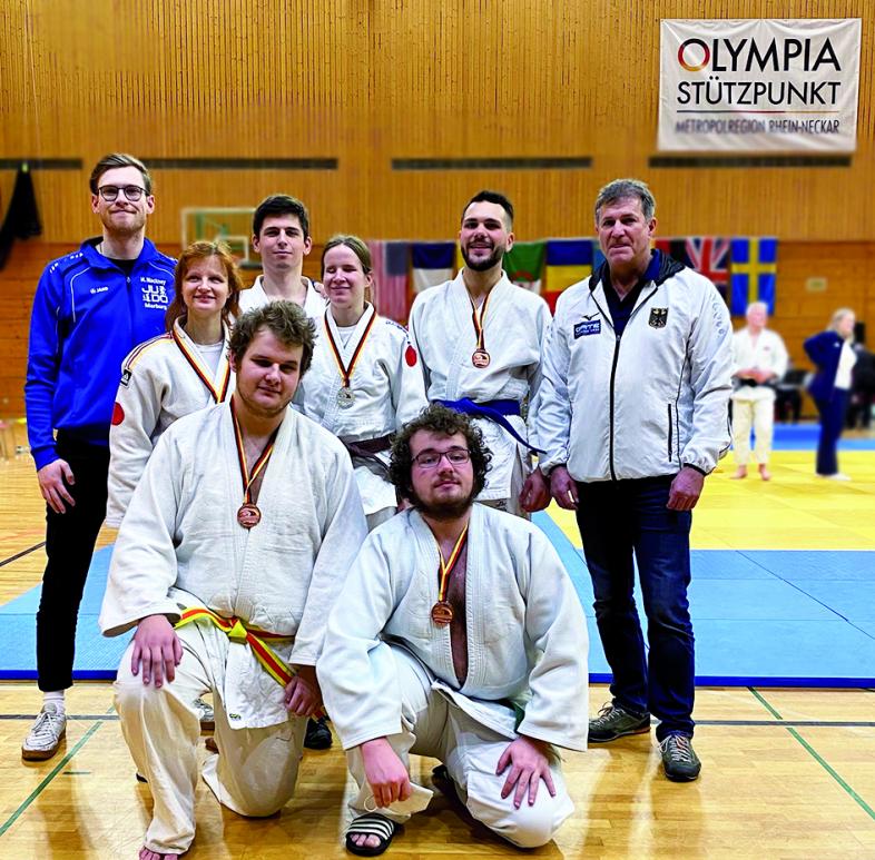 Foto der Marburger Para-Judo-Delegation in Judoanzügen und mit Medaillen behängt. In der Mitte sind die Sportlerinnen und Sportler, rechts und links die Trainer.