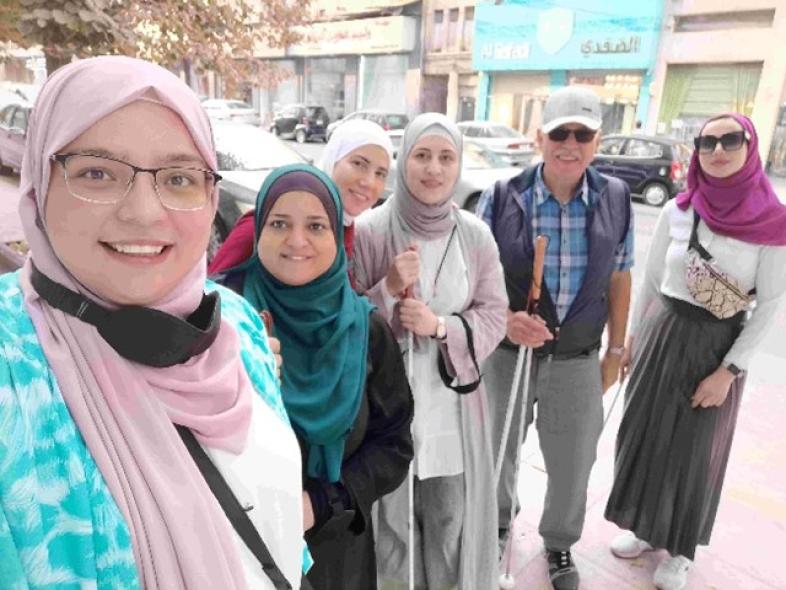 5.	Gruppenbild auf der Straße: Dania, Asmaa, Yosur, Maisaa, Gert Willumeit und Ayat lächeln in die Kamera.
