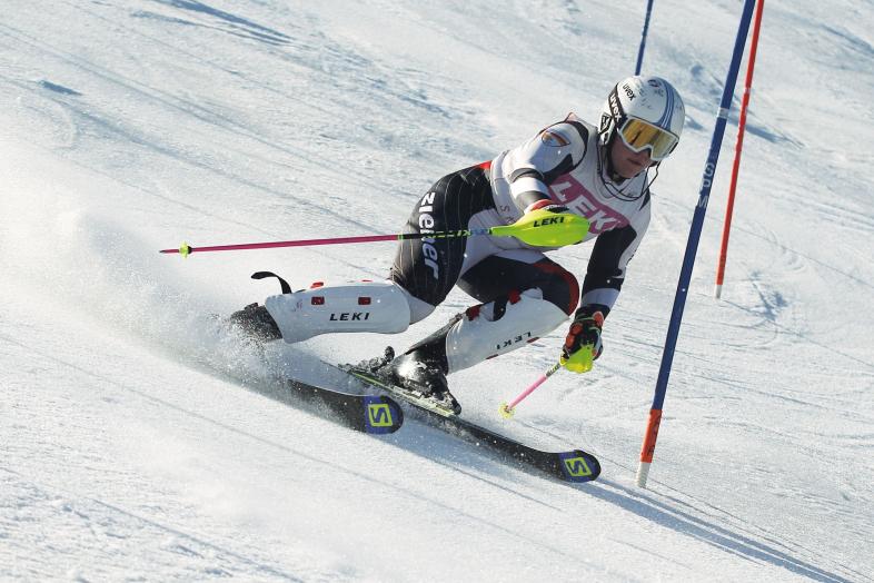 Hanna Gieg fährt im Skianzug mit Helm und Brille seitwärts gelehnt um eine Slalomstange.