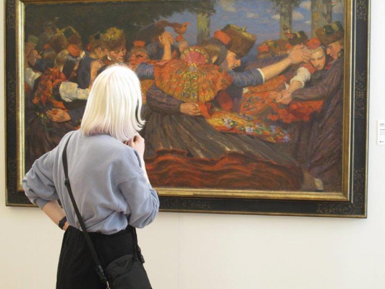 Eine junge Frau betrachtet das Gemälde "Schwälmer Tanz"