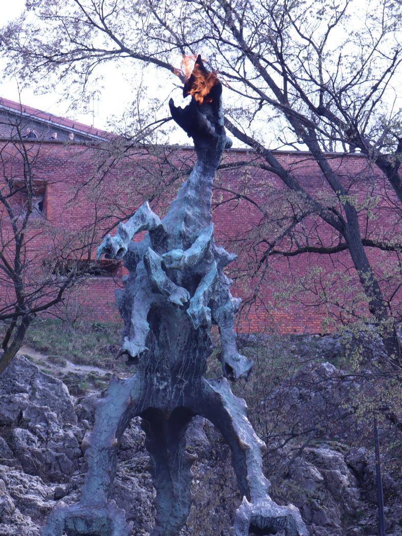 Die Statue des feuerspeienden Wawel-Drachen vor der Burgmauer in Krakau zeigt eine furchteinflößende, bronzene Gestalt, aus deren Maul eine echte Flamme lodert.