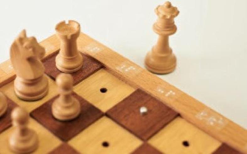 Eine Detailansicht eines taktilen Schachbretts aus Holz. 