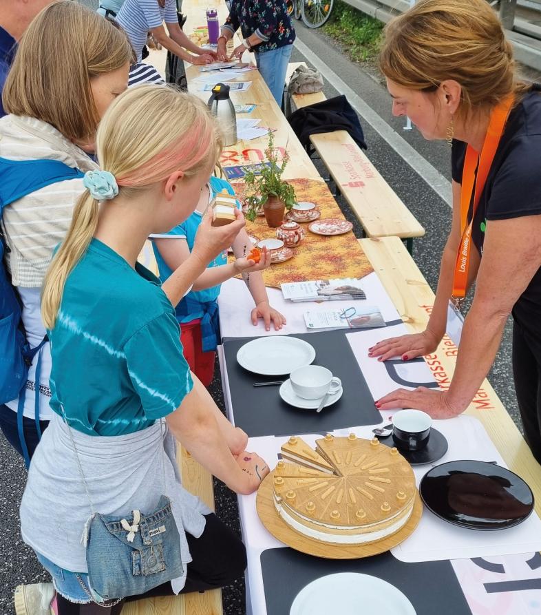 blista-Mitarbeiterin Ute Mölter zeigt zwei Kindern, wie eine kontrastreiche Kaffeetafel aussieht.