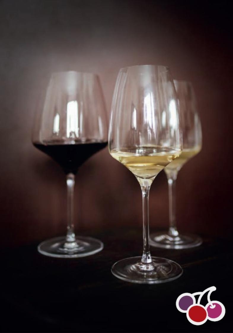 Drei Weingläser mit Rot-und Weißwein vor einem dunklen Hintergrund.