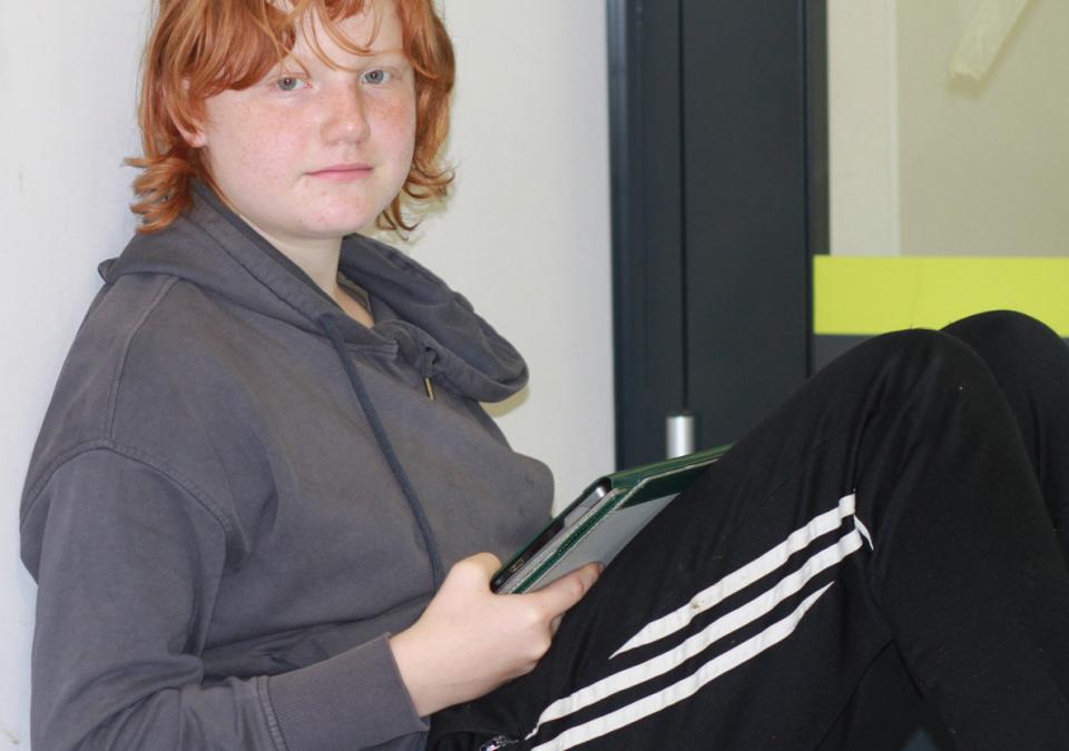 Bild 5 von 6: Ein Mädchen sitzt am Boden und schaut zu den Betrachtenden hin