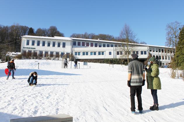 Auf dem verschneiten blistaCampus sieht man rodelnde Schüler*innen und beobachtende Lehrkräfte
