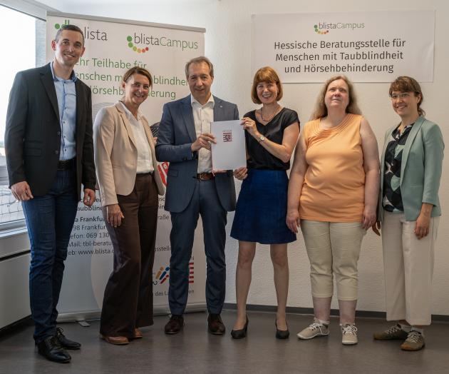 Vor blista-Bannern stehen 6 Personen: Sozialministerin Heike Hofmann übergibt Patrick Temmesfeld den Förderbescheid.