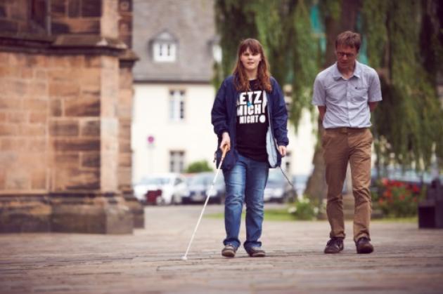 Eine Schülerin und ein Rehabilitationslehrer erkunden den Vorplatz der Elisabethkirche in Marburg
