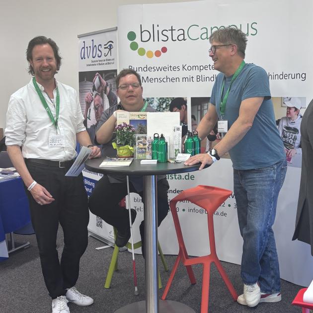 Christian Gerhold, Thorsten Büchner und Otfrid Altfeld stehen an einem Stehtisch vor der Messewand