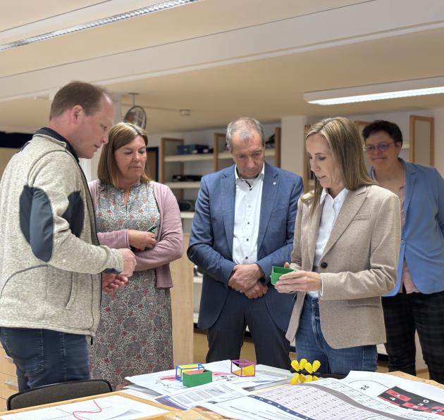 Astrid Wallmann bei ihrem Besuch in der blista: sie hat 3D Gedruckte Modelle in der Hand, mehrere Personen scheinen im Gespräch mit ihr. 